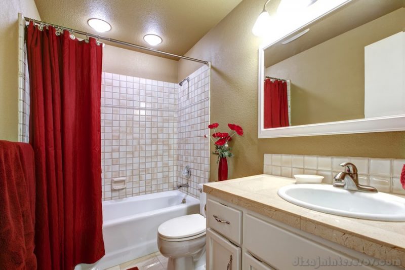 Small simple beige and red bathroom with white sink.