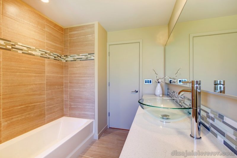 light tones bathroom with designed beige wall, glass vessel sink and decorative flower vase