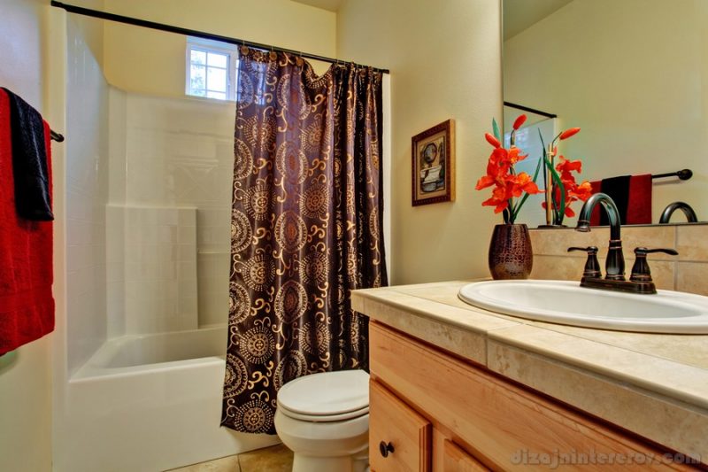 Bathroom with small window. VIew of washbasin cabinet decorated with beautiful red flower