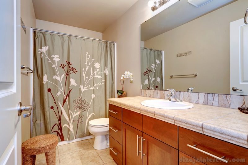 Bathroom interior in soft ivory color with wooden vanity cabinet and large mirror