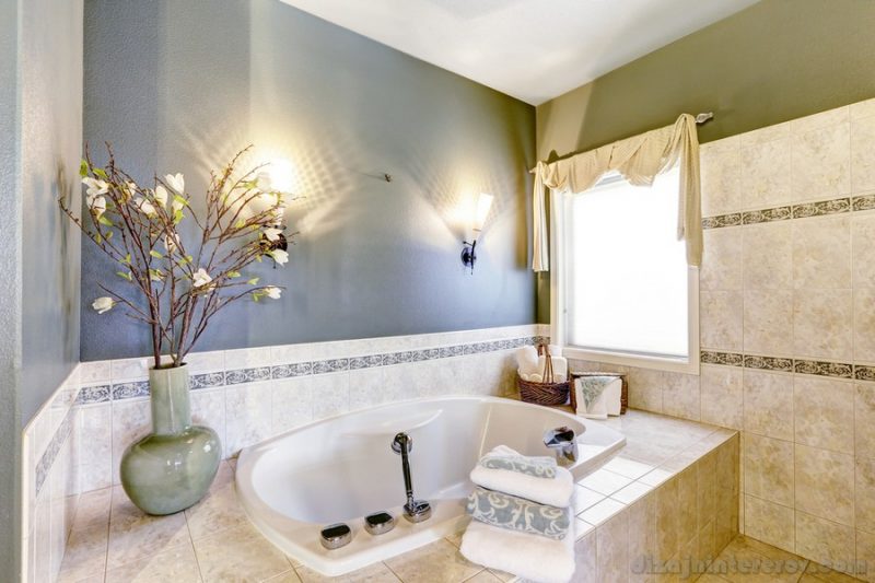 Bathroom with bath tub, tile trim and contrast green and lavender walls