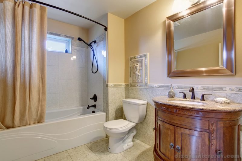 Gorgeous bathroom with tan shower curtain, and gold framed mirror.