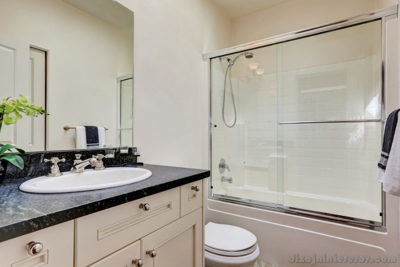 White bathroom interior with glass shower and vanity with black counter top. Northwest, USA