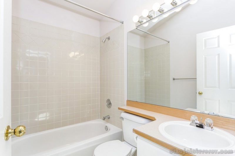 Renovated interior of a white bathroom with tiled wall.
